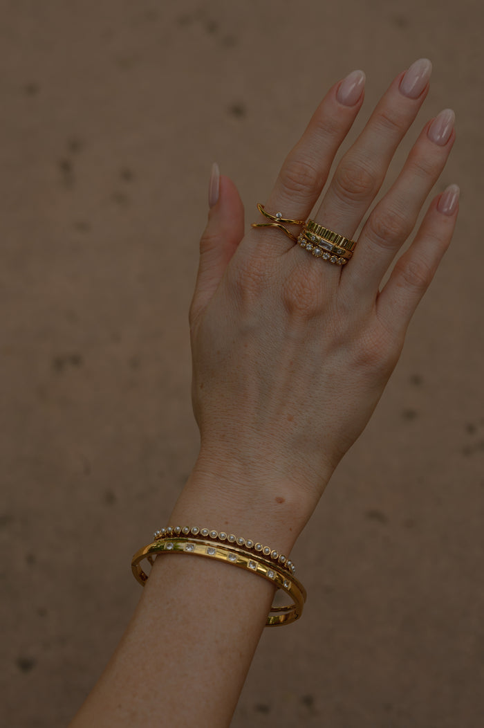 Detail view of the gold Celeste emerald cut ring on a white background