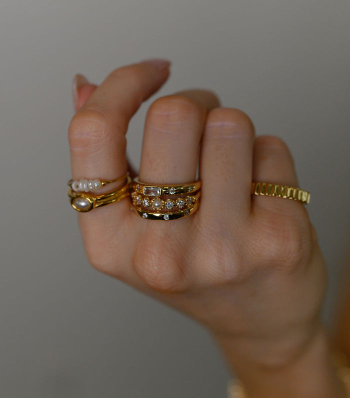 Studio close up of the gold Celeste emerald cut ring on a white background