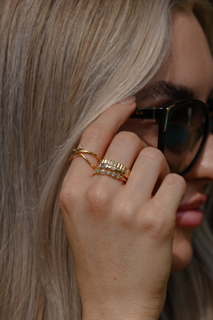 Close view of the gold Celeste emerald cut ring on a white background