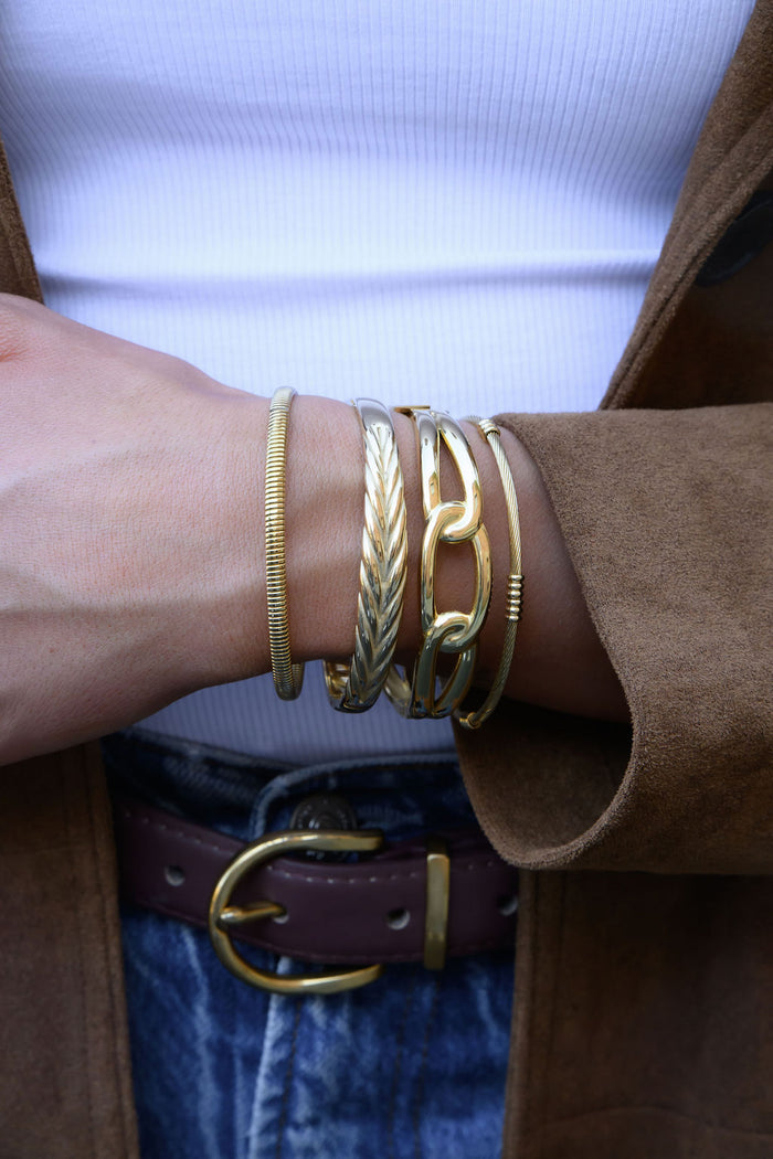 A brown coat sleeve with gold bangles