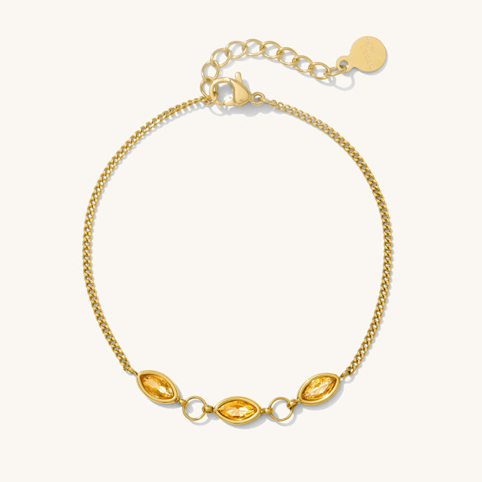 Close up of a gold bracelet with stone accents on a white background