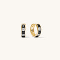 Close up of gold and black huggie earrings on a white background