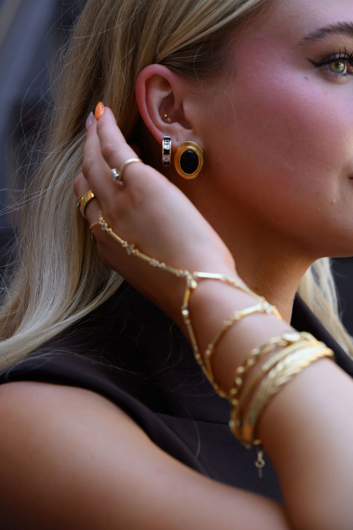 A woman wearing bold gold earrings, rings, and bracelets