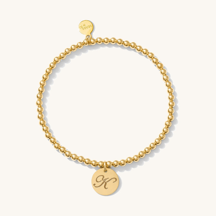 Close up of a gold bracelet with charm on a white background