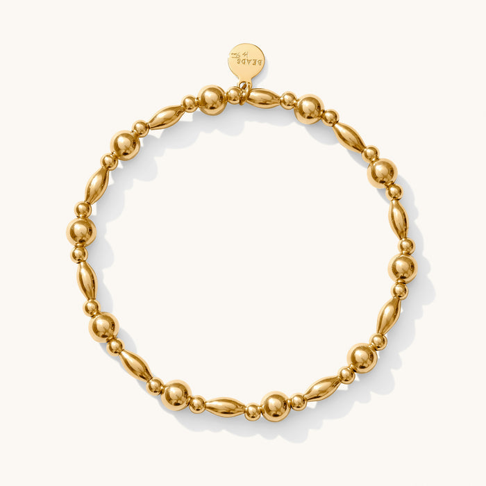 Close up of a gold bead bracelet on a white background