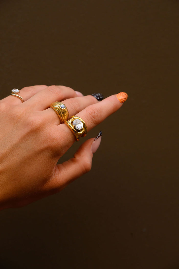The Comet ring, a gold dome band with rippling grooves and a sparkling stone