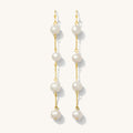Close up of gold pearl drop earrings on a white background