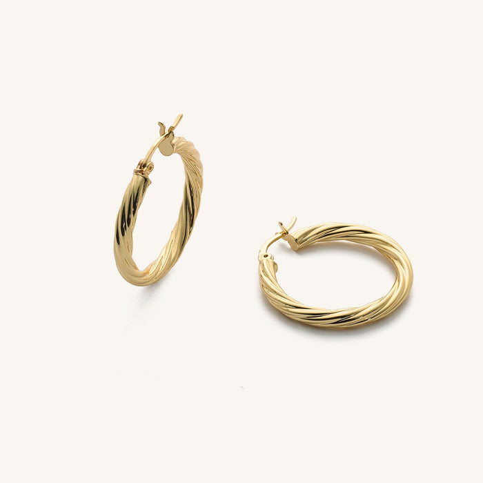 Close up of textured gold hoops on a white background