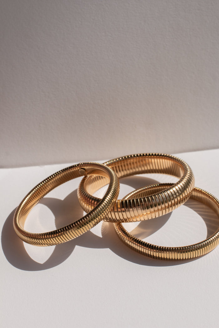 A stack of gold bangles on a white background