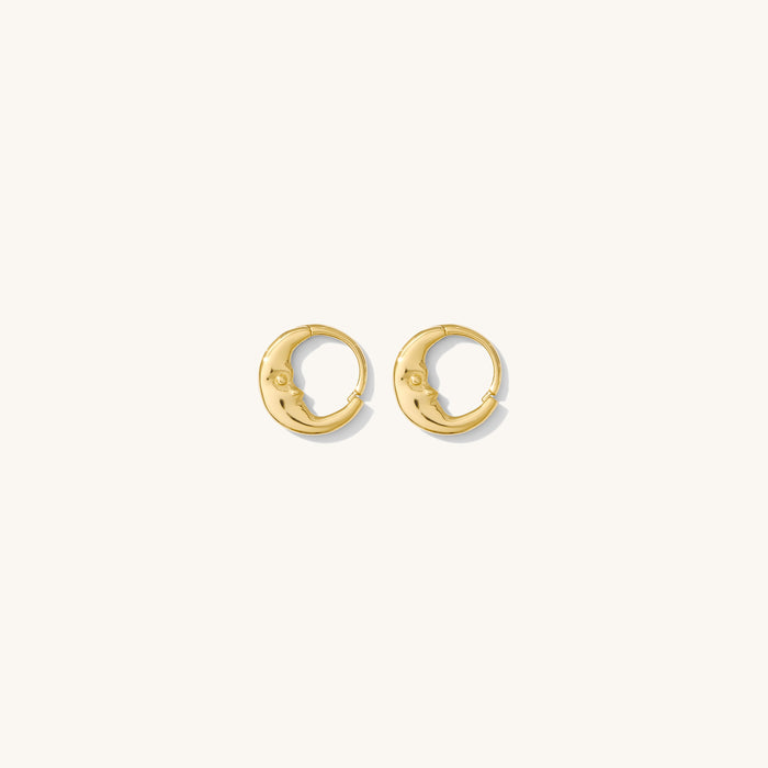 Close up of gold huggie earrings on a white background
