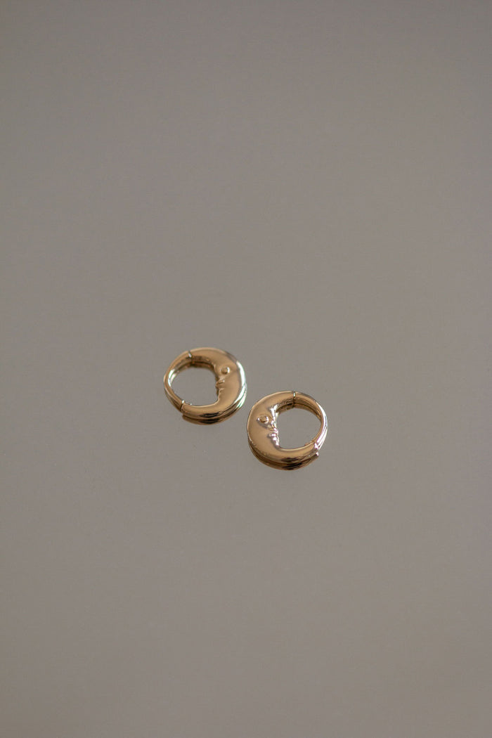 Gold huggie earrings on a grey background