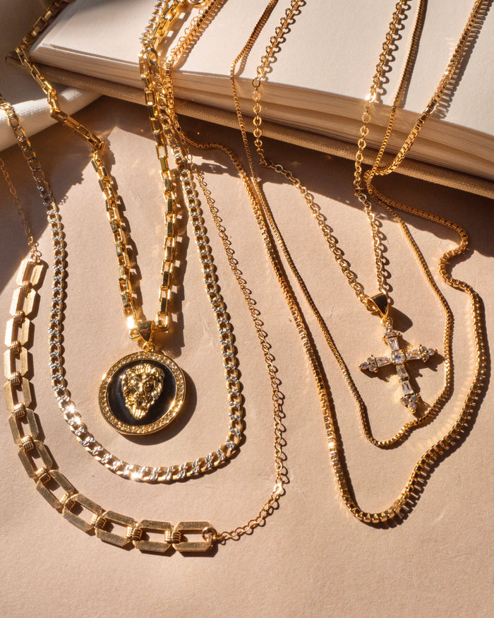 The gold-plated Cruz necklace sparkling on a layered neckline