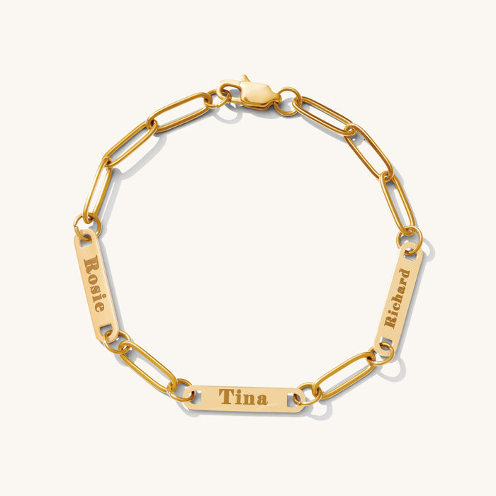 Close up of a gold link bracelet with engraved bar accent beads on a white background