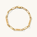 Close up of a gold link bracelet with engraved bar accent beads on a white background