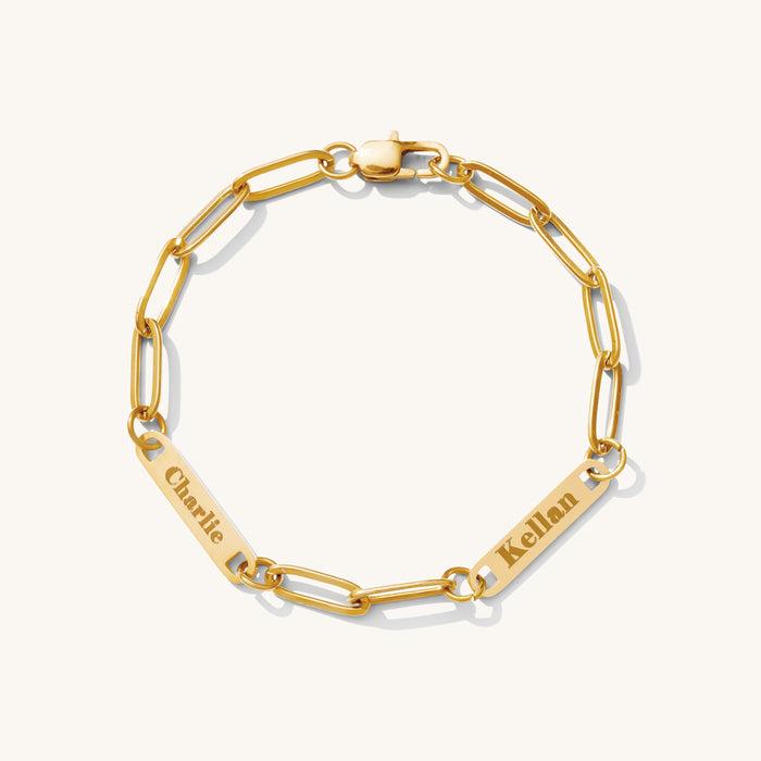 Close up of a gold link bracelet with engraved bar accent beads on a white background