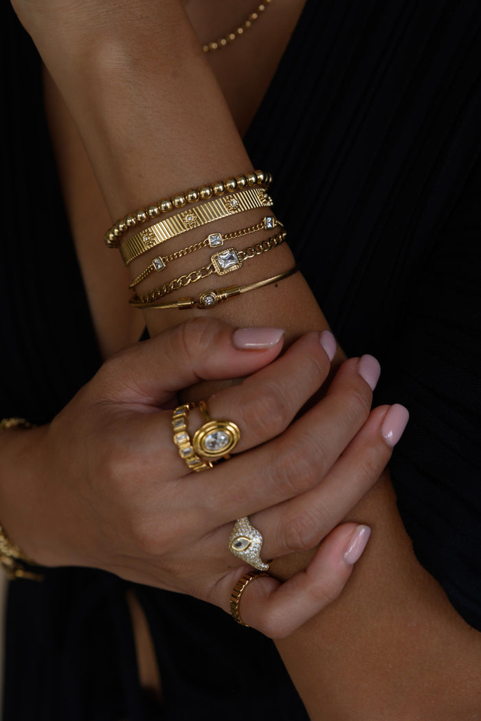 Close up of a woman's arms with gold rings and bracelets