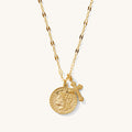 Close up of the gold Desiree cross and coin necklace on a white background