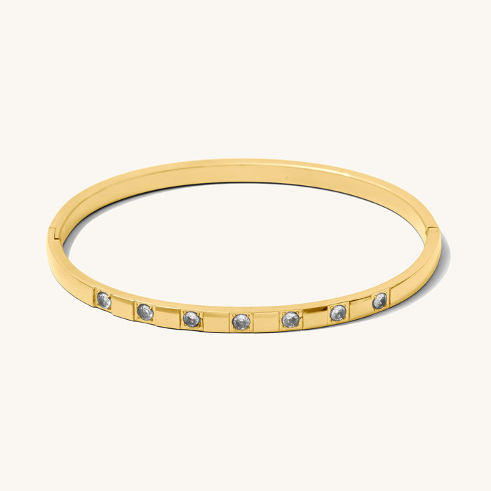 Close up of gold bangle with stones on a white background