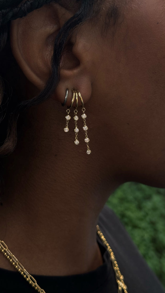 Close-up side view of a woman wearing gold earrings and necklaces in a black shirt