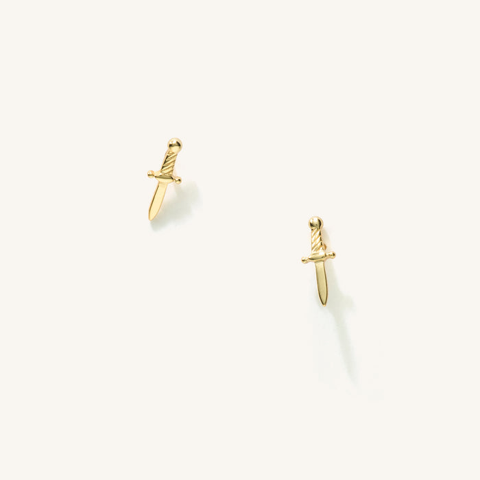 Close up of sword-shaped stud earrings on a white background