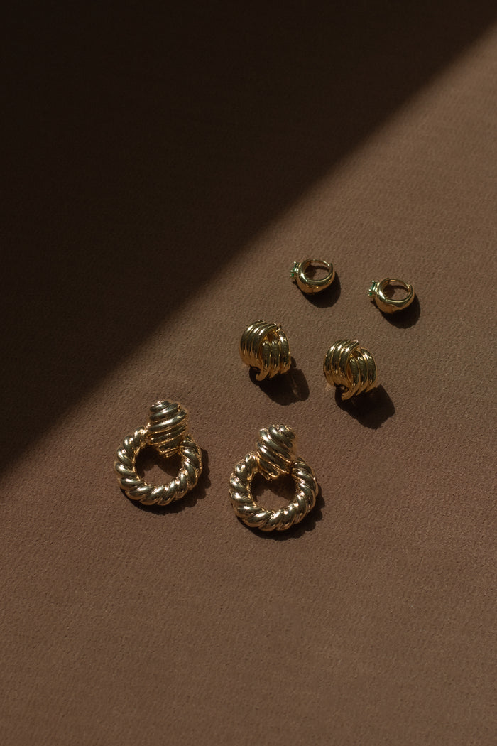 Three pairs of gold earrings on a brown background