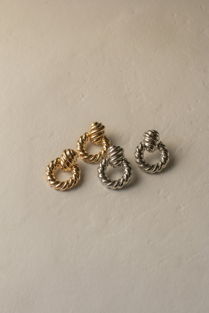 Matching gold and silver earrings on a neutral background