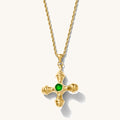 Close up of the gold Dune necklace with an emerald center stone on a white background
