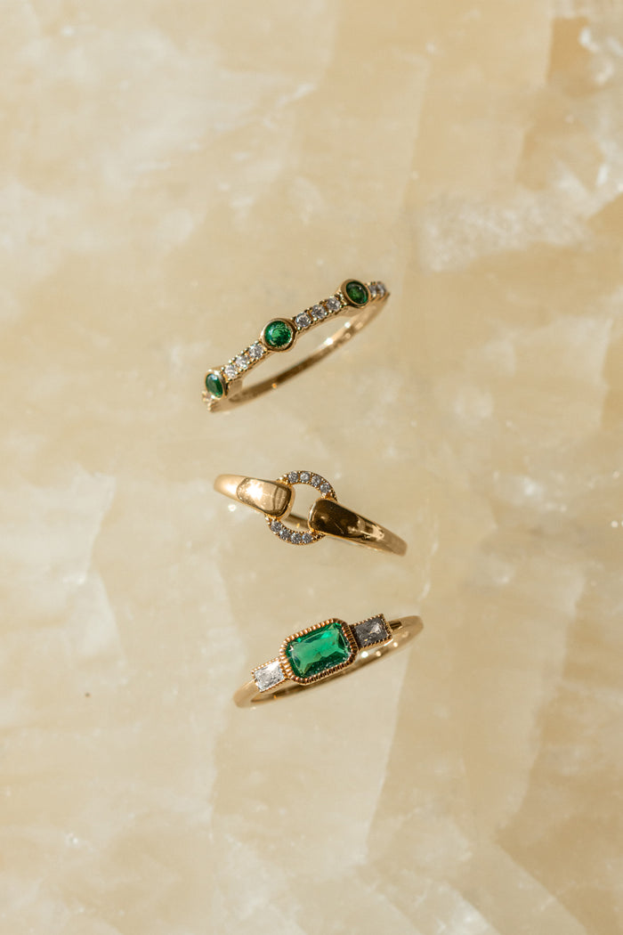 Close view of the textured bezel holding the emerald on the East West ring