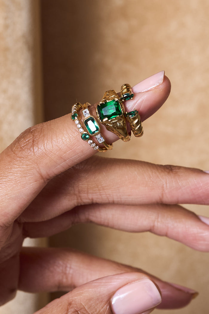 Horizontal emerald centerpiece with clear accent stones on the East West ring