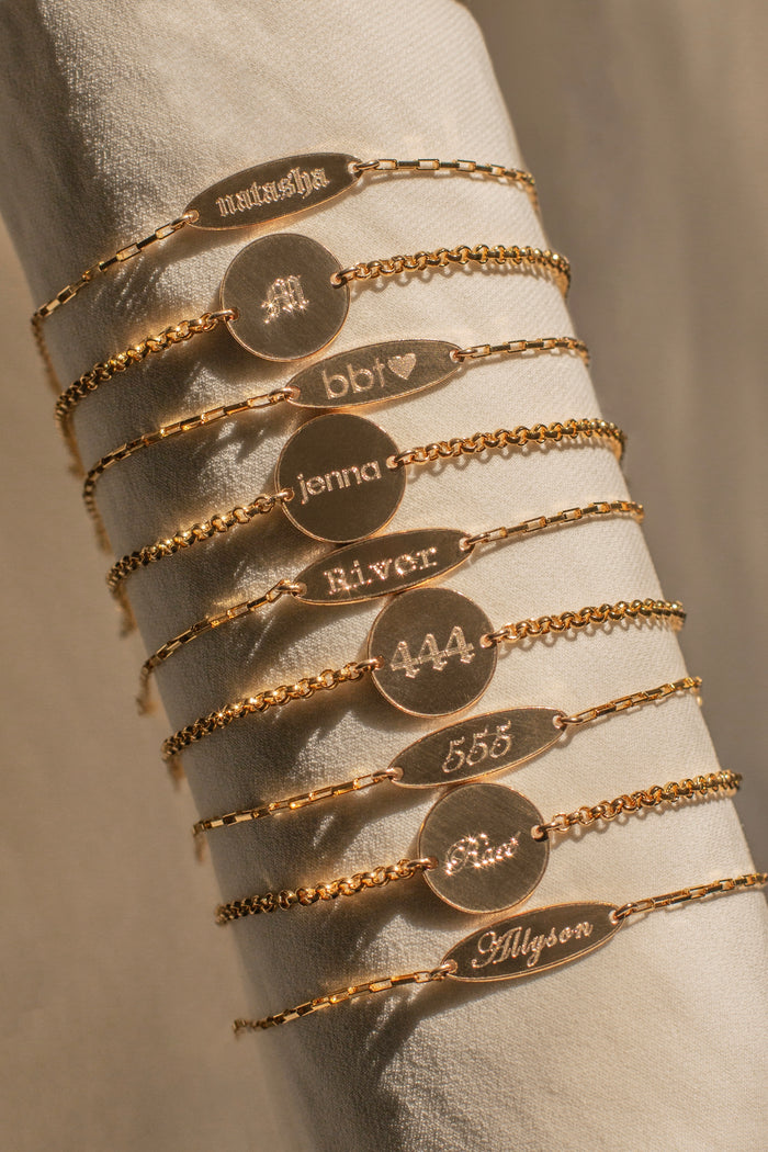 A cloth jewelry display with assorted engraved tag gold bracelets