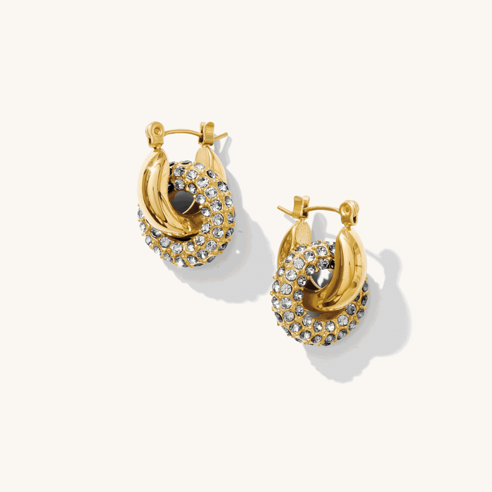 Close up of gold huggie earrings with removable stone charms on a white background