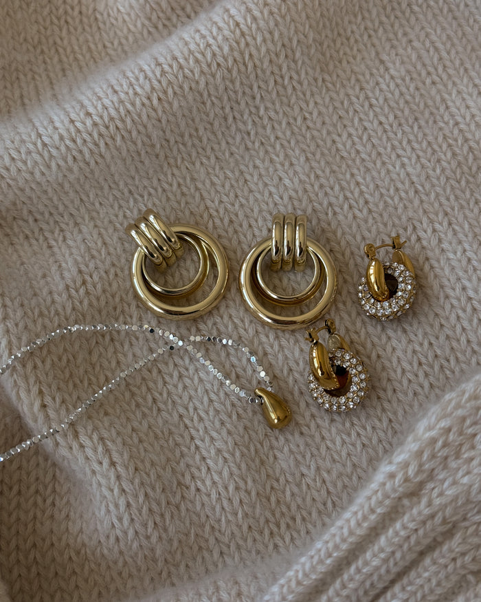 Earrings and a necklace on a cream fabric background