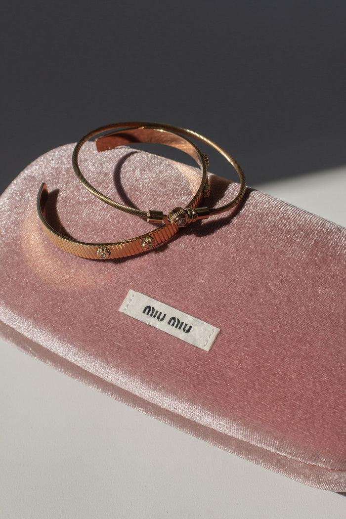Two gold bangles on a pink velvet case