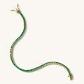 Close up of a tennis bracelet with green stones on a white background