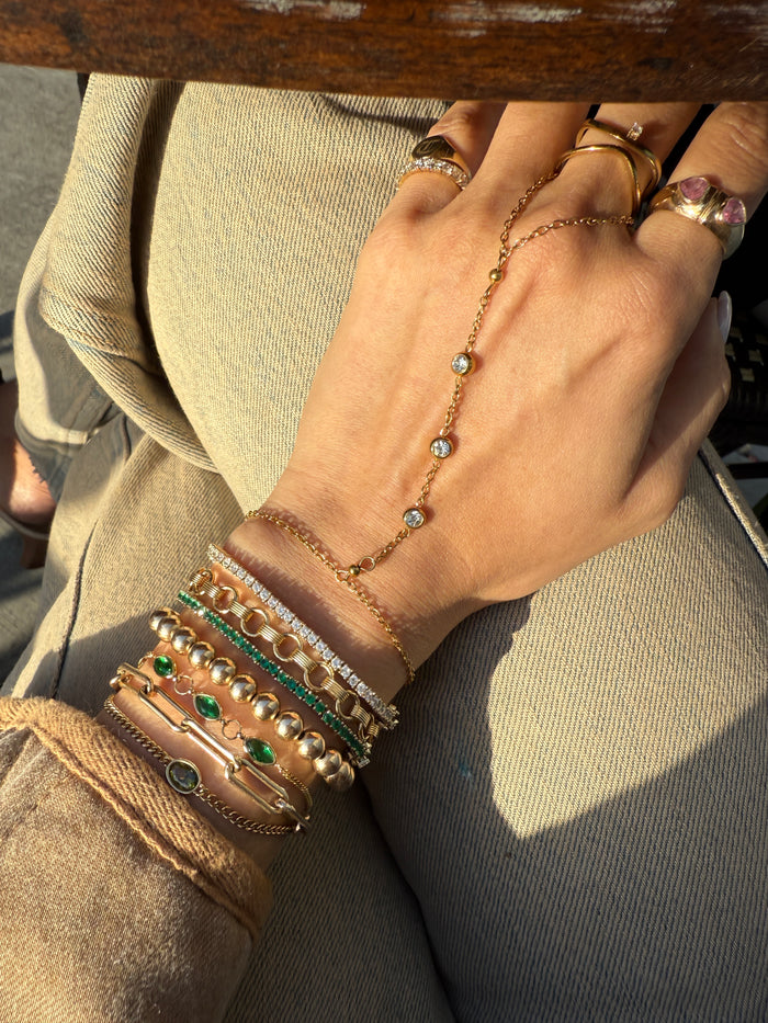 Close up of a hand with assorted gold and stone bracelets and rings