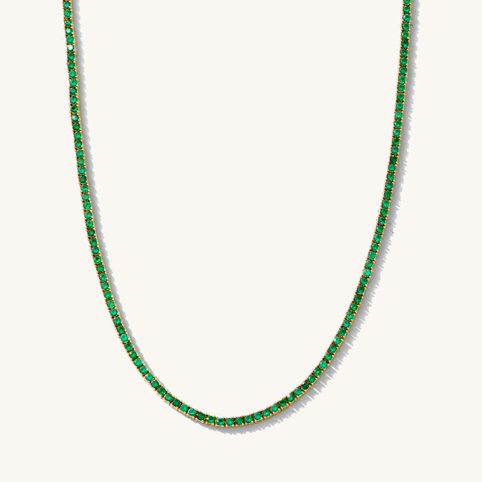 Close up of the gold Emerald Everyday tennis necklace on a white background
