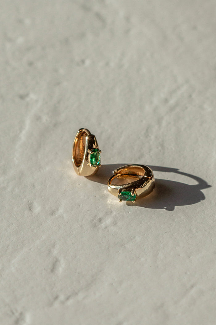 Gold and green earrings on a white background