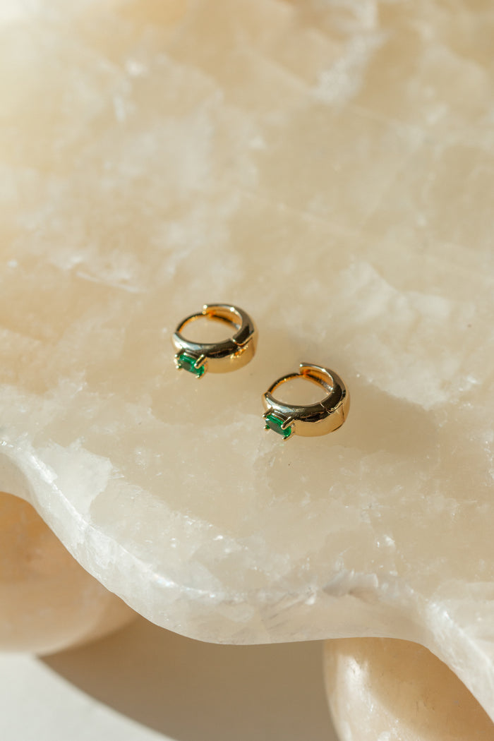 Gold earrings on a cream stone slab