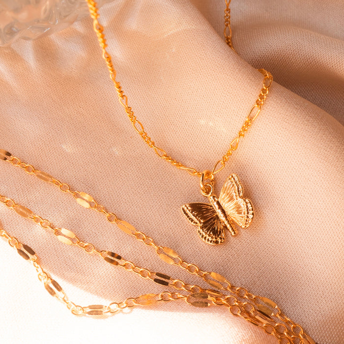 Emily butterfly necklace worn layered with dainty gold chains