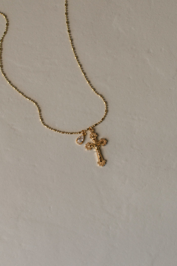 Close view of the bezel-set pear gem hanging beside the Ernestina cross