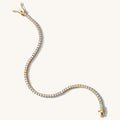 Close up of a gold tennis bracelet on a white background