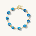 Close up of a gold bracelet with blue evil eye beads on a white background