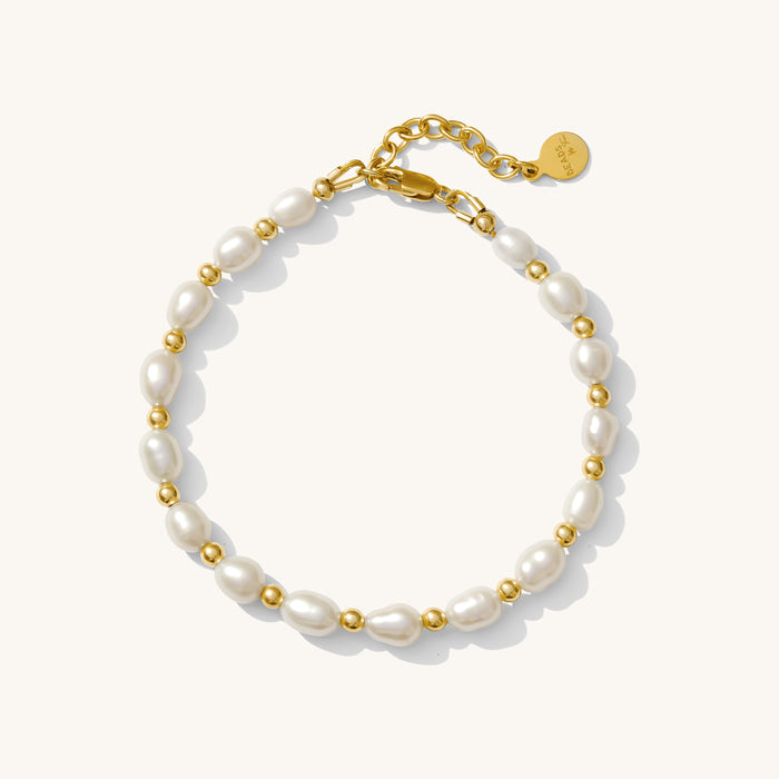 Close up of a gold bracelet with pearl beads on a white background