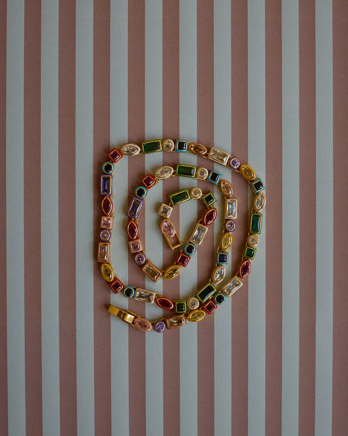 Colorful gemstone necklace on a striped background