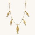 Close up of the gold Go Fish statement necklace on a white background