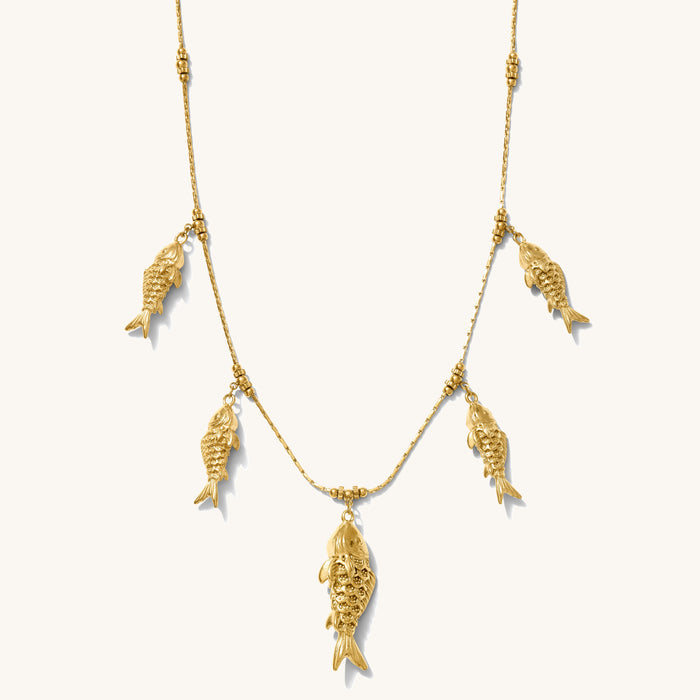 Close up of the gold Go Fish statement necklace on a white background