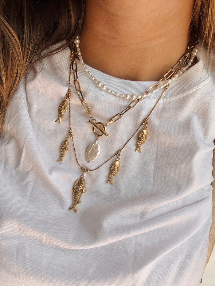 A detail view of the gold Go Fish statement necklace by Beads by Tara