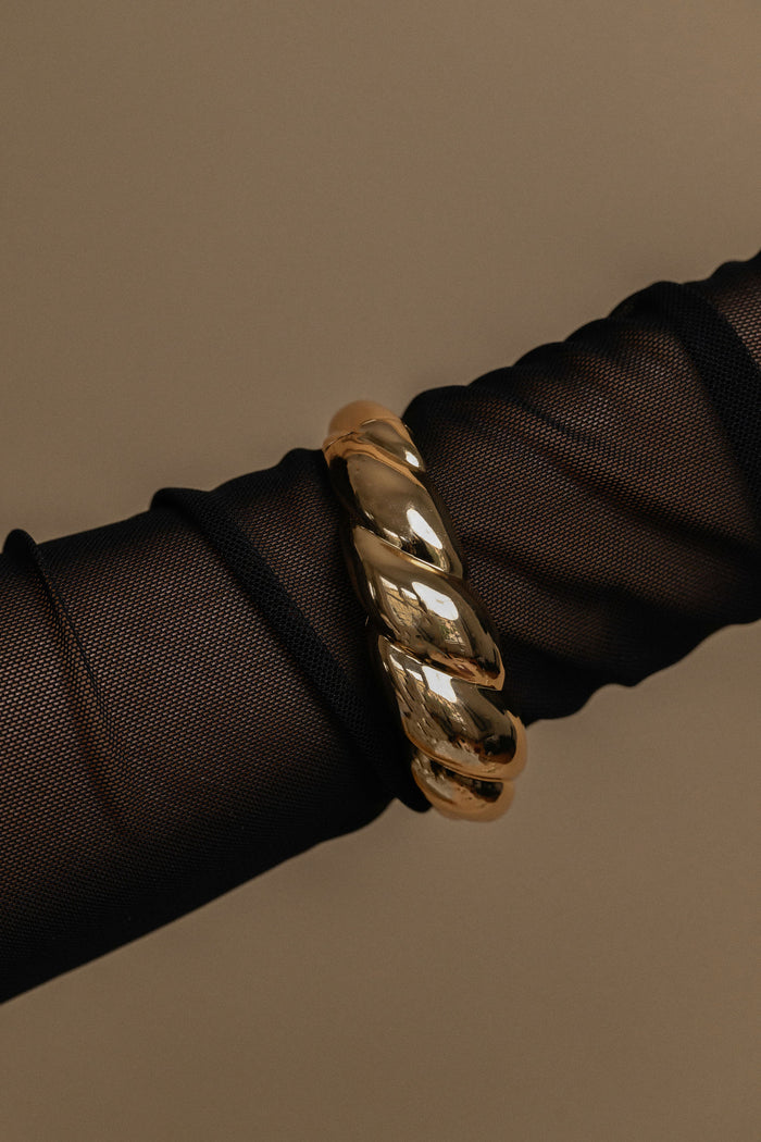 Gold bracelet on a black mesh sleeve