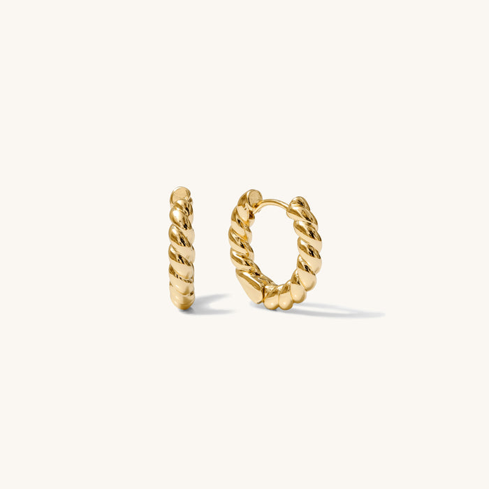Close up of textured gold hoops on a white background
