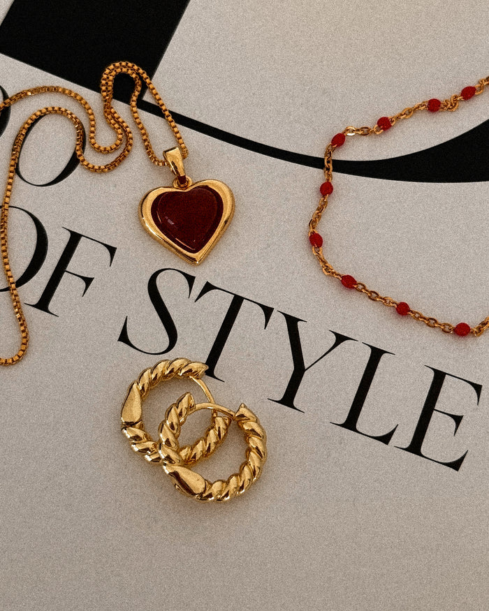 A necklace, bracelet, and hoop earrings on a magazine background